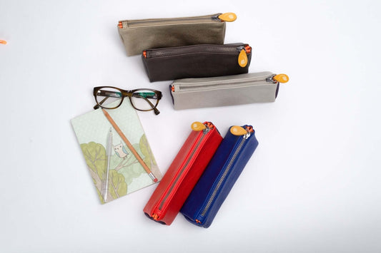 Union Makeup Pouch collection with vegan leather, metallic zippers, and wood zip pullers, displayed alongside notebook and eyeglasses