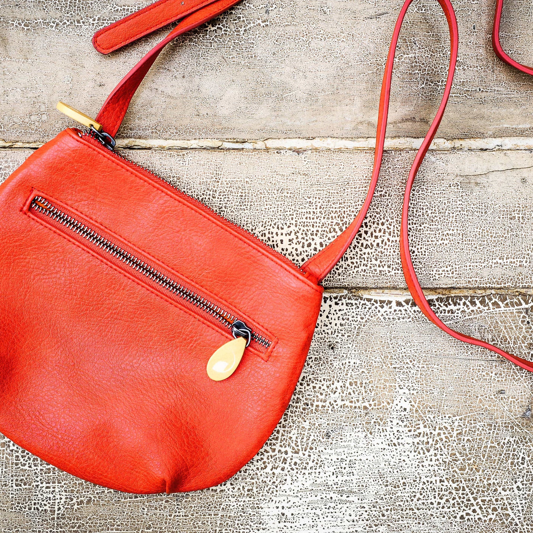 Willoughby Crossbody Bag in vegan leather with two zippered compartments and adjustable strap, bright orange color.