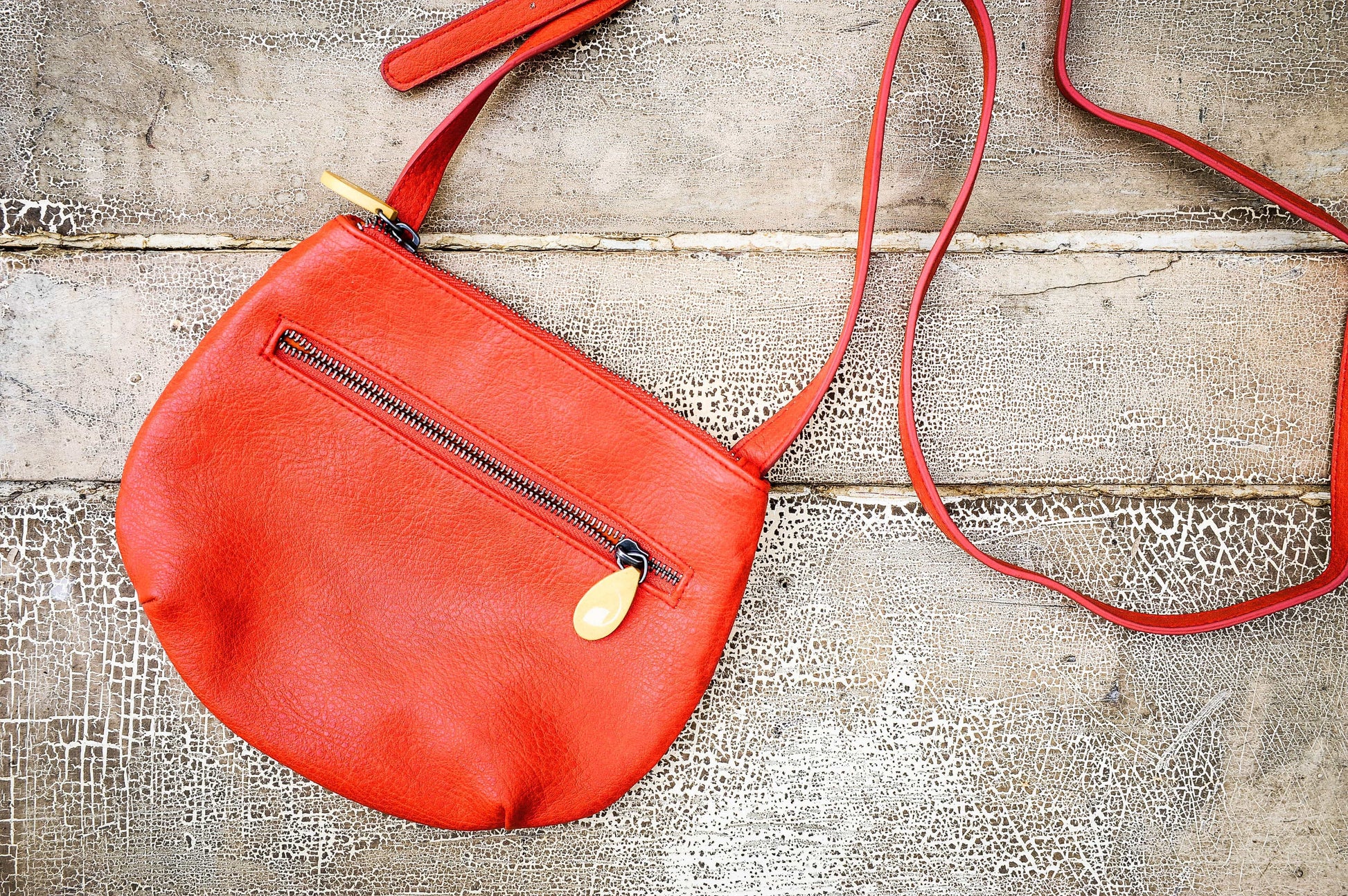 Willoughby Crossbody Bag in vegan leather with two zippered compartments and adjustable strap, bright orange color.