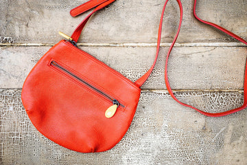 Willoughby Crossbody Bag in vegan leather with two zippered compartments and adjustable strap, bright orange color.