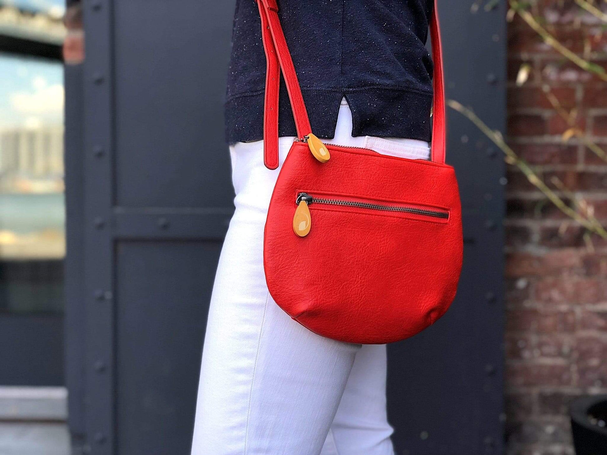 Red Willoughby Crossbody Bag in vegan leather with 24" adjustable strap, shown worn over the shoulder, featuring two zippered compartments