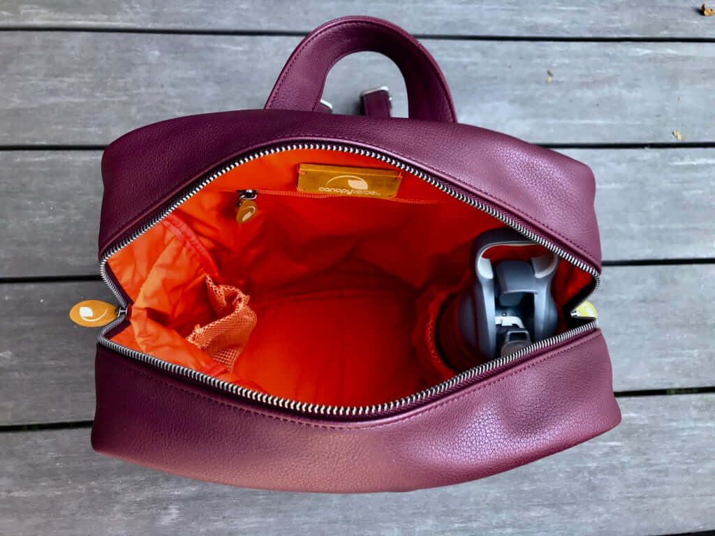 Open Lenox Vegan Leather Backpack showing spacious interior with orange lining, water bottle pocket, and multiple compartments.