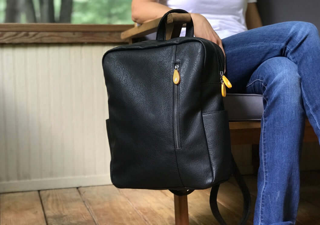 Lenox Vegan Leather Backpack with sleek minimalist design hanging on a chair, perfect for office to weekend use.