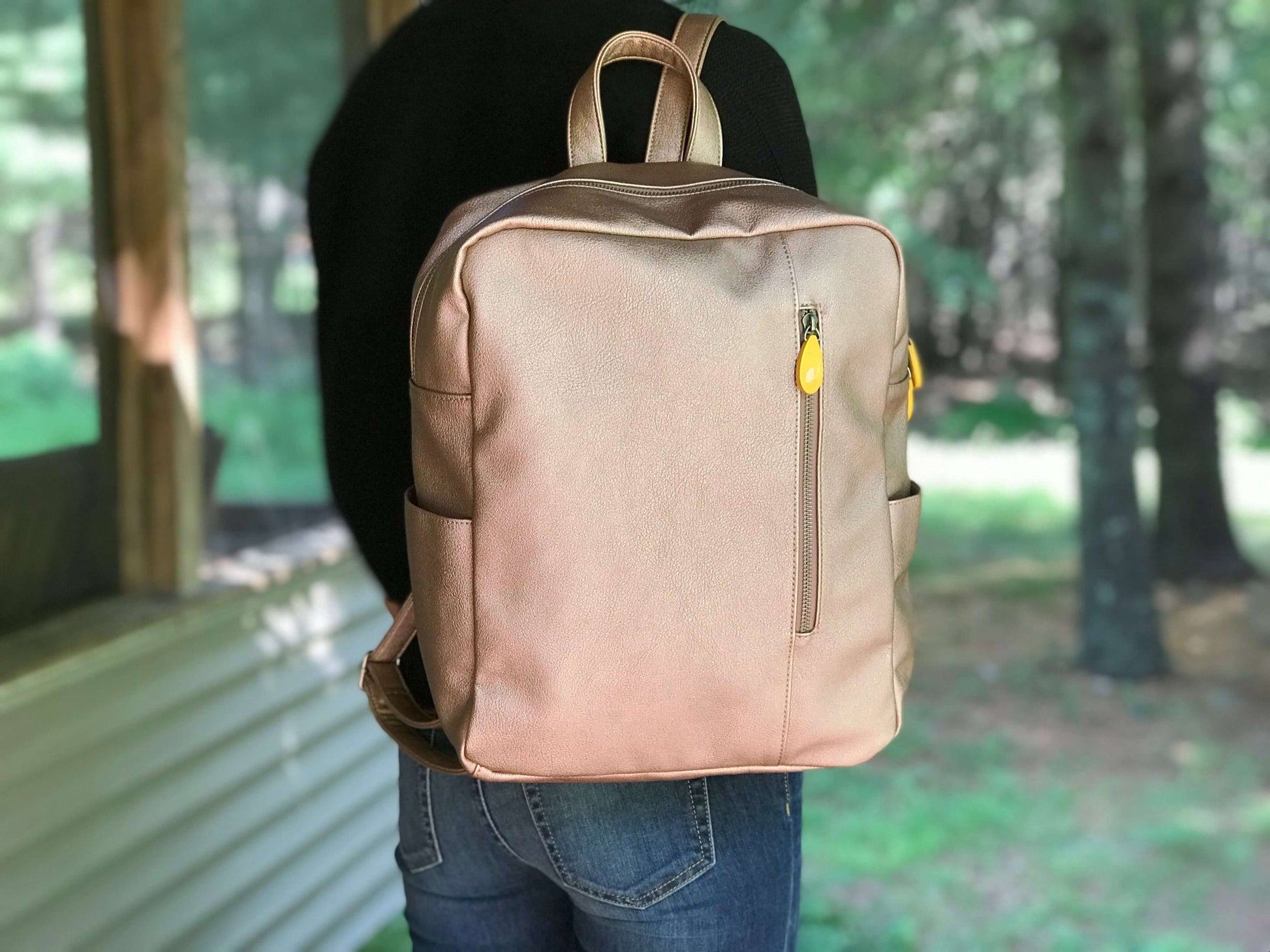 Person wearing Lenox Vegan Leather Backpack with sleek and minimalist design, showing comfortable straps and front zipper pocket.