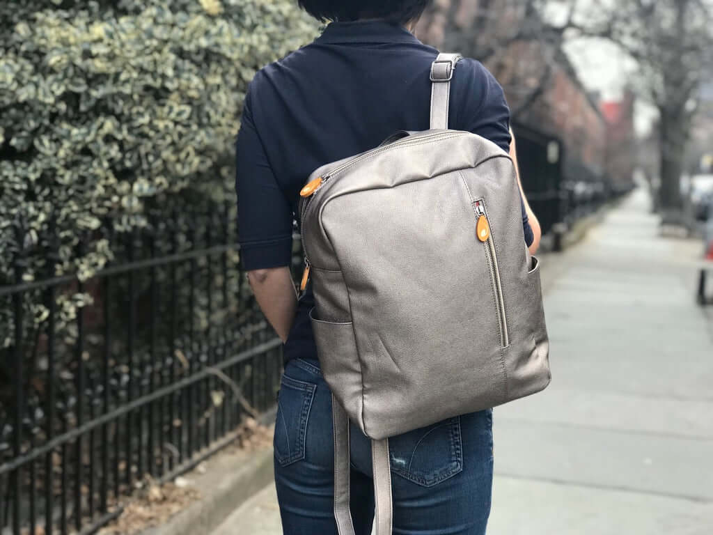 Woman wearing Lenox Vegan Leather Backpack on a city street with slim design and comfortable straps