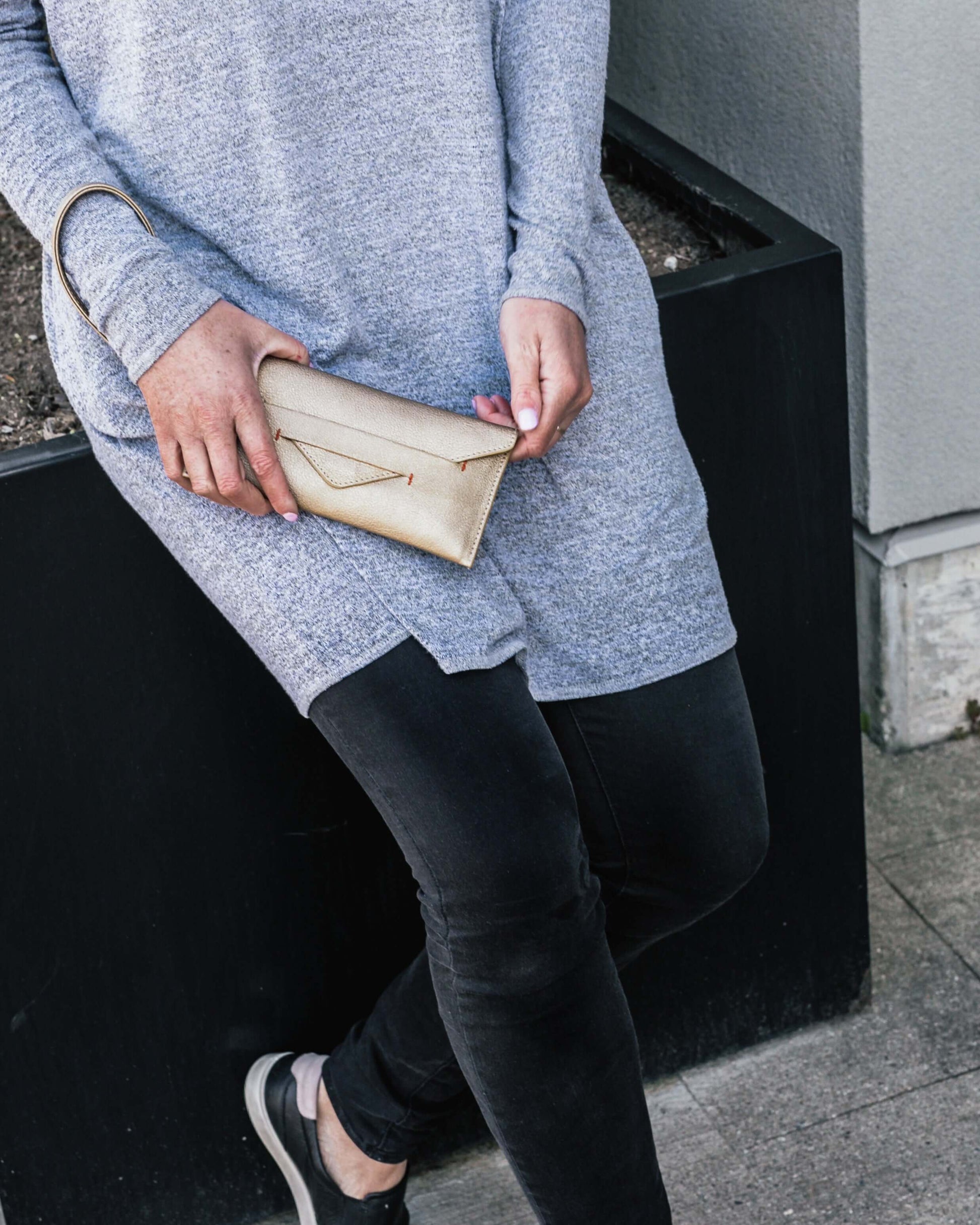 Woman holding Delancey Wristlet Wallet made of vegan leather with detachable strap.