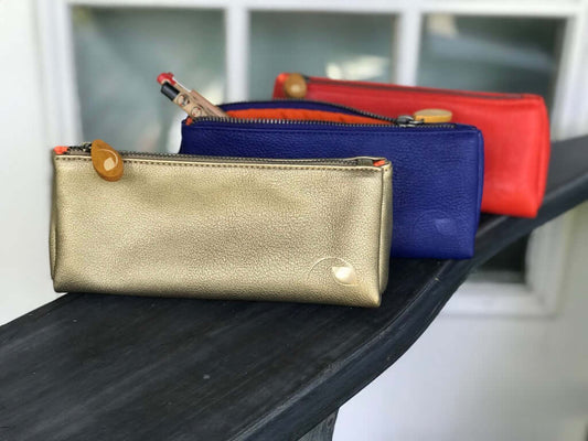 Union Makeup Pouch in gold, blue, and red, featuring a stylish metallic zipper, vegan leather, and chic wood zip puller.