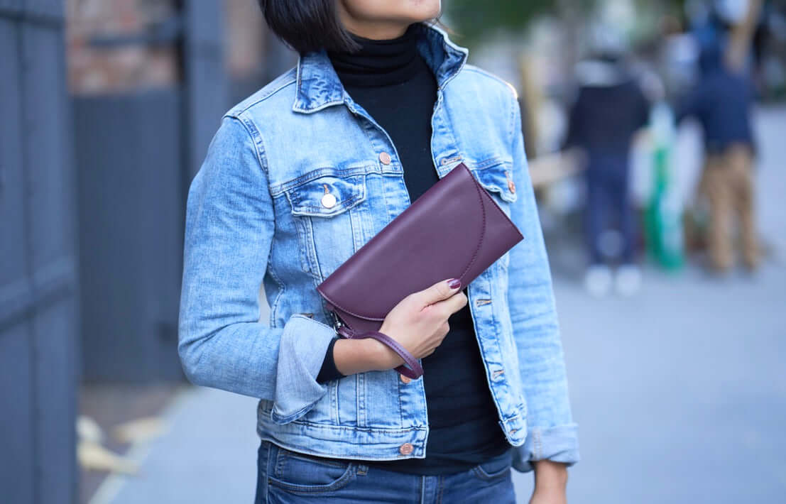 Person holding a Clark Phone Wallet in vegan leather, wearing a denim jacket outside.